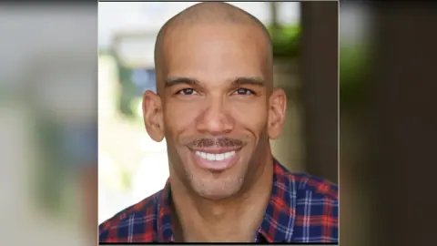 A smiling man in a photograph from the HairDot.Ink website